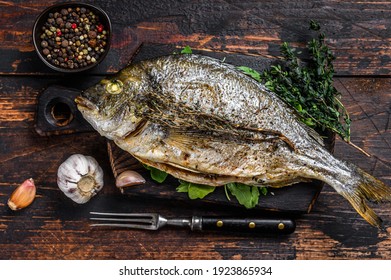 Grilled Dorada Sea Bream Fish On A Cutting Board. Dark Wooden Background. Top View