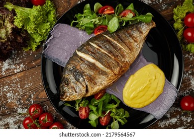 Grilled Dorado Fish On The Black Dish Wooden Background