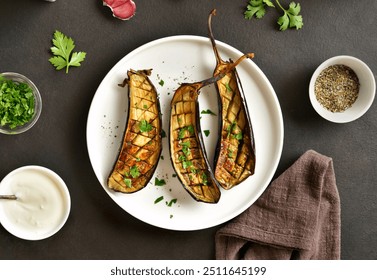 Grilled eggplant (aubergine) on white plate over dark stone background. Top view, flat lay - Powered by Shutterstock