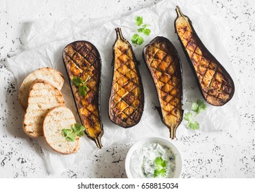 Grilled eggplant and sauce tzatziki on a light background, top view. Baked aubergine   