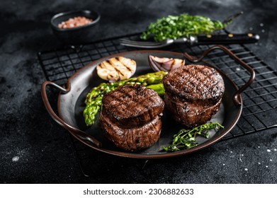 Grilled Fillet Mignon Steak with roasted asparagus. Black background. Top view.