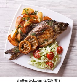 Grilled Fish With Fried Potatoes And Salad On A Plate. Top View Closeup 