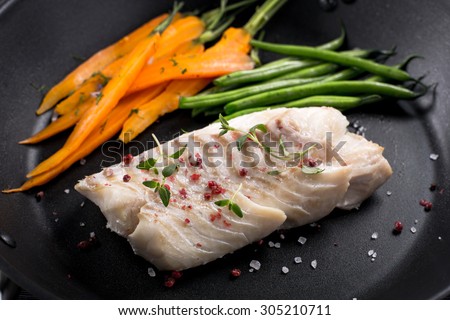 grilled fish with green beans and carrots on frying pan