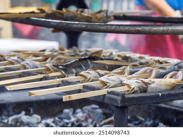 Grilled fish on skewers over open fire, outdoor cooking, barbecue, grilled seafood concept - Powered by Shutterstock