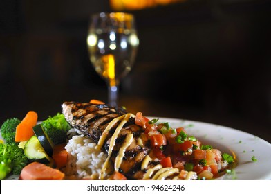 Grilled Fish On A White Plate With Rice And Vegetables Glass Of Wine