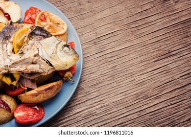 Grilled fish with potato and lemon on wooden table - Shutterstock ID 1196811016