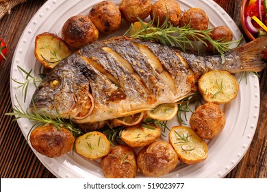 Grilled fish with roasted potatoes and vegetables on the plate