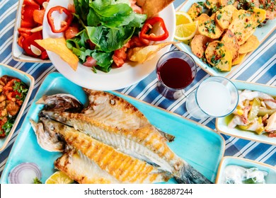 Grilled Fish, Salads And Vegetables. Seafoods, Grilled Meat, Meze, Raki, Ouzo, Appetizers And Salads On The Table In Greek Or Turkish Fish Restaurant For Dinner Or Lunch At The Beach.