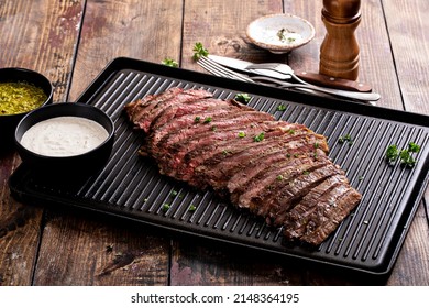 Grilled Flank Steak With Chimichurri And Horseradish Sauce On A Grill Pan On Wooden Table