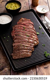 Grilled Flank Steak With Chimichurri And Horseradish Sauce On A Grill Pan On Wooden Table