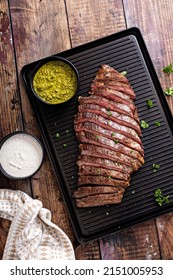 Grilled Flank Steak With Chimichurri And Horseradish Sauce On A Grill Pan On Wooden Table