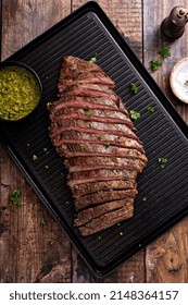 Grilled Flank Steak With Chimichurri Sauce On A Grill Pan On Wooden Table