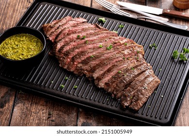 Grilled Flank Steak With Chimichurri Sauce On A Grill Pan On Wooden Table