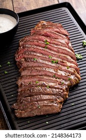 Grilled Flank Steak With Horseradish Sauce On A Grill Pan On Wooden Table