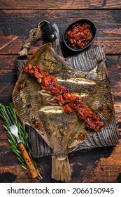 Grilled Flounder Or Plaice With Tomato Sauce On Wooden Cutting Board. Dark Wooden Background. Top View