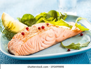 Grilled Fresh Salmon Steak Showing The Texture Of The Flesh Served With A Wedge Of Lemon And Rocket And Leafy Green Salad