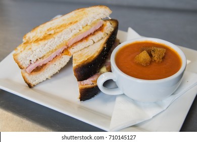 A Grilled Ham And Cheese Sandwhich With Tomato Soup In A Teacup.