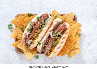 Grilled Hot Dogs With Mustard, Onion, Relish And Corn Chips On A Picnic Table