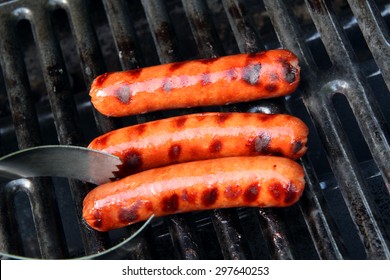 Grilled Hot Dogs With Tongs On The Grill