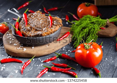 grilled kebab grilled meat steak lies in an iron frying pan, on a wooden vintage old board rustic, chili, with tomatoes, sauce, dill onions, on the table top, side, bottom angle shot, fork and knife, 