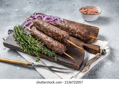 Grilled kofta kofte shish kebab from mince lamb and beef meat on Skewer. Gray background. Top view.