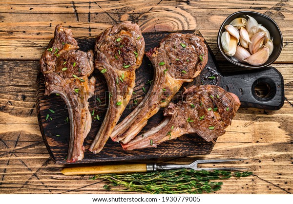 Grilled lamb mutton meat chops\
steaks on a cutting board. wooden background. Top\
view.