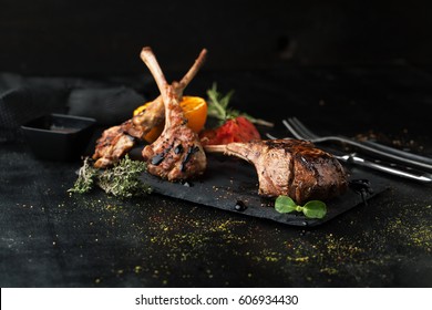 Grilled lamb rack with spices and sauce on a dark background