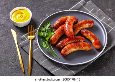 grilled lamb sausages, bangers on a plate on a concrete table, horizontal view from above