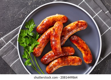 grilled lamb sausages, bangers on a plate on a concrete table, horizontal view from above, flat lay,  close-up