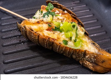 Grilled Lobster Tail Frying On A Grill Pan, With Melted Butter, Lemon Juice, Zest, Chives, Parsley, Garlic, And Salt, Close-up View.