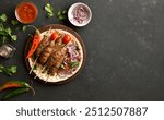 Grilled lula kebab with fresh vegetables on flat bread on wooden platter on dark background with free space. Top view, flat lay, closeup