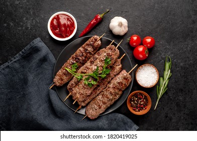 Grilled Lula kebab on skewers with spices in a black plate on a stone background 
