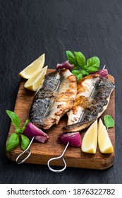 Grilled  Mackerel And Red Onion On Skewers On Wooden Board On Black Stone Background 