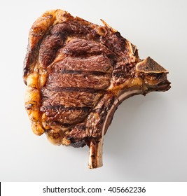 Grilled Marinated Cote De Boeuf , Or Bone-in Ribeye Steak Ringed With Fat In A Close Up Overhead View On White