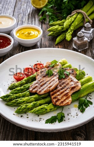 Grilled meat and asparagus on wooden table 