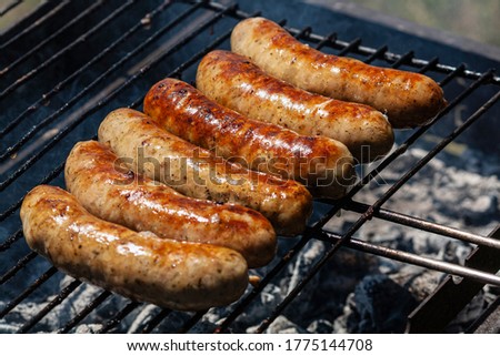 A lot of grilled meat sausages on the grill in the summer.