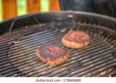 Grilled Meat - Two Burnt Burgers On An Outdoor Grill