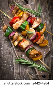 Grilled meat and vegetable kebabs on wooden cutting board