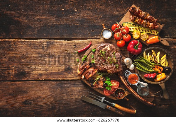 Grilled meat\
and vegetables on rustic wooden\
table