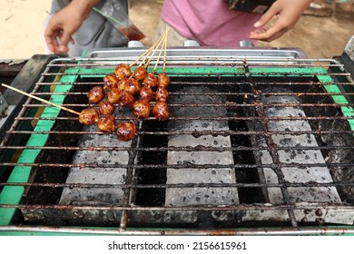 Grilled meatballs, in Indonesia called "Pentol Bakar". Stabbed with sticks of coconut leaves. Usually sold by peddlers