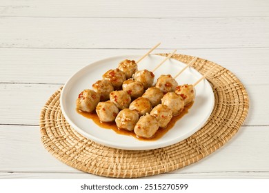 Grilled meatballs poured with dipping sauce on a beautifully decorated plate.