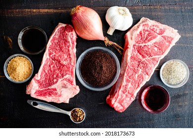 Grilled NY Strip Steak With Coffee Rub Ingredients: New York Strip Steaks, Red Wine, Coffee Grounds, And Spices On A Dark Wood Background