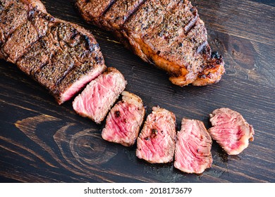 Grilled NY Strip Steak With Coffee Rub: Grilled New York Strip Steaks On A Dark Wood Background