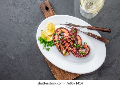 Grilled octopus on white plate serverd with white wine , top view. Seafood.