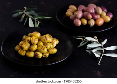 Grilled olives on dark background. Tasty grilled green olives in the plate. Mixed marinated olives (green and purple) in the background - Powered by Shutterstock