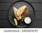 Grilled perch fillet served on a plate on a dark wooden background. Top view, flat lay. Copy space