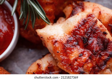 Grilled Piece Of Meat. Crispy Chicken Wings. The Texture Of The Meat Is Very Close Up. Seasoning In The Form Of Ketchup And Sprigs Of Rosemary.