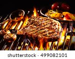 Grilled pieces of delicious rump steak garnished with herbs and sauce alongside mushrooms and vegetables over flames