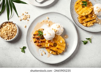 Grilled pineapples with rum honey glaze, coconut icecream and grated peanuts, tropical vegan dessert, top view.  - Powered by Shutterstock