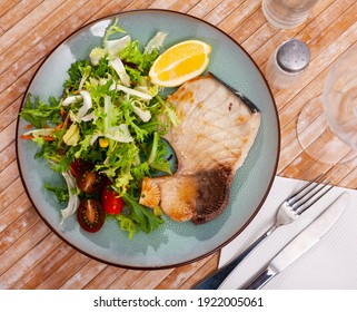 Grilled porbeagle shark fish steak garnished with mix of salads, tomato, carrot and lemon